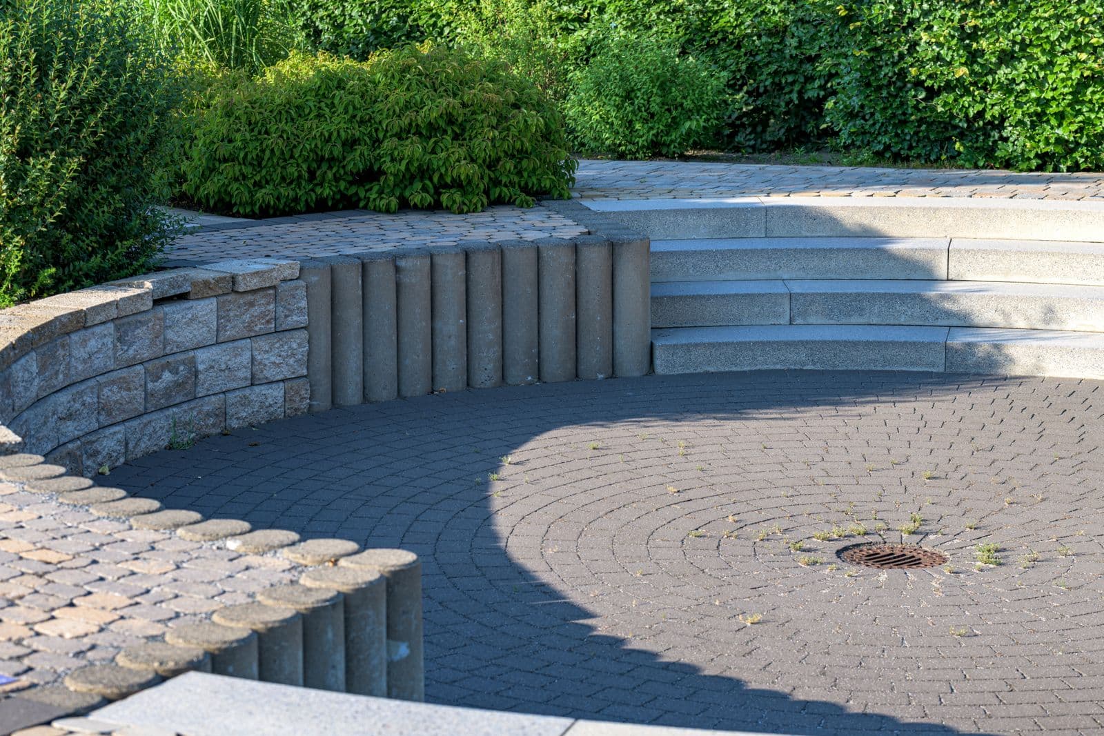 Garten- und Landschaftsbau: rund gepflasterter Sitzplatz mit Natursteinmauer und Hecke